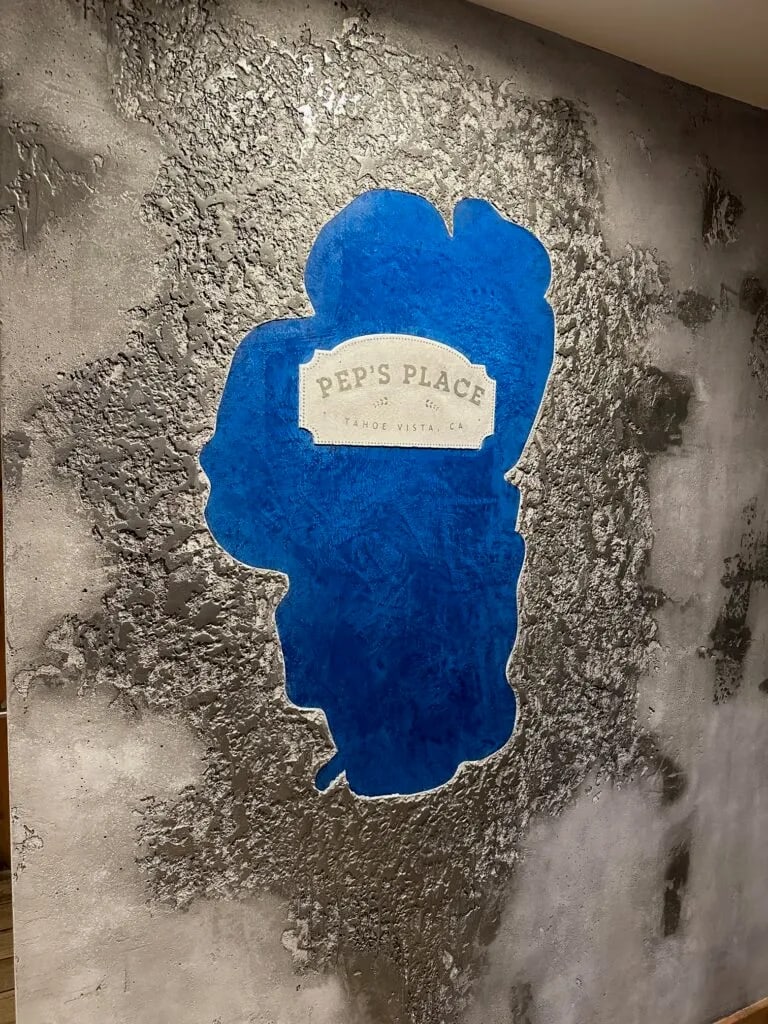 A Lake Tahoe silhouette in blue plaster set into a rough grey wall at Pep's Place, Tahoe Vista